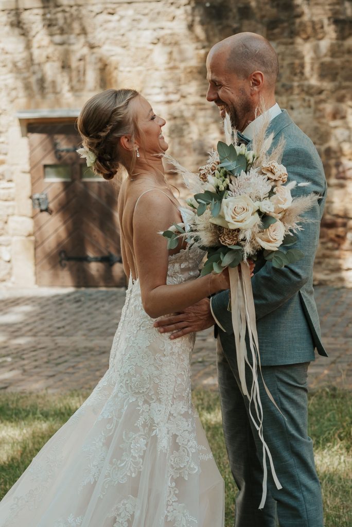 Glückliches Brautpaar beim First Look mit Brautstrauss Komplettplanung Katrin Hoessler fiderallala Traumhochzeiten