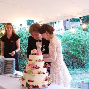 Brautpaar schneidet Hochzeitstorte an bei Gartenhochzeit